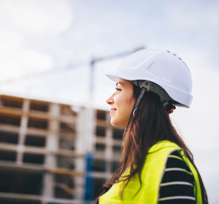 Woman wearing hard hat and fluorescent safety vest.
