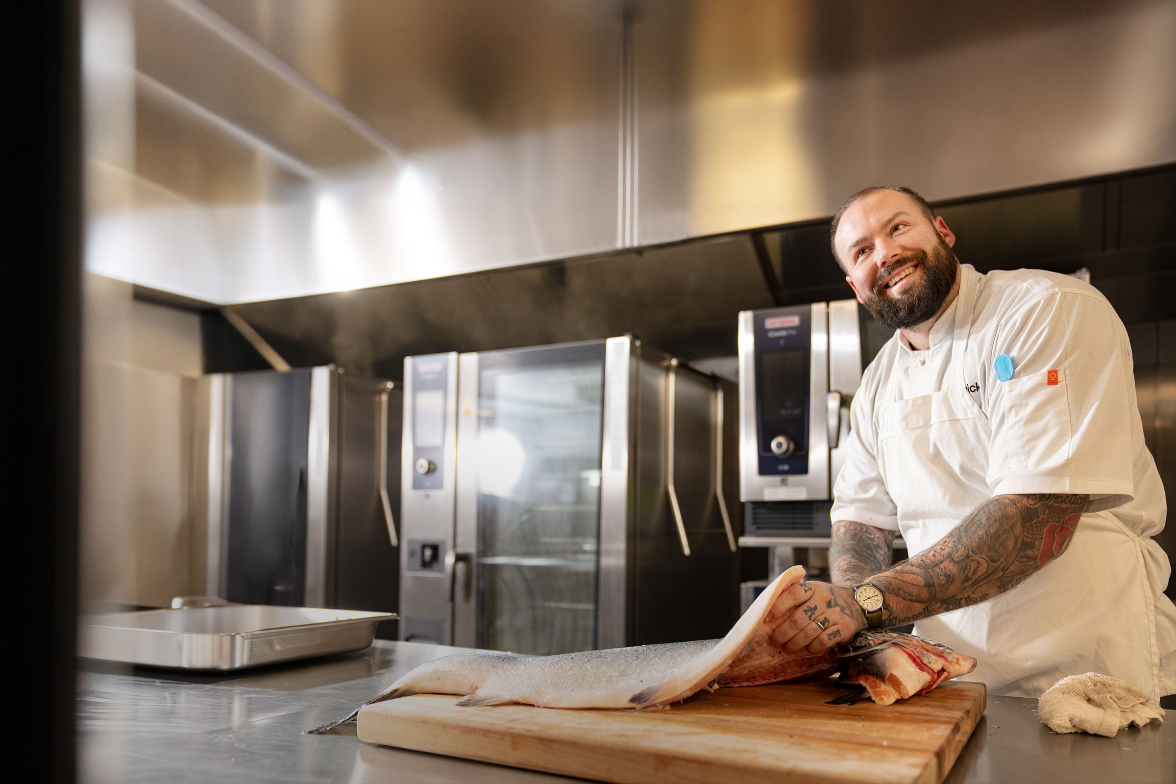 Chef fileting a large fish in a commerical kitchen.