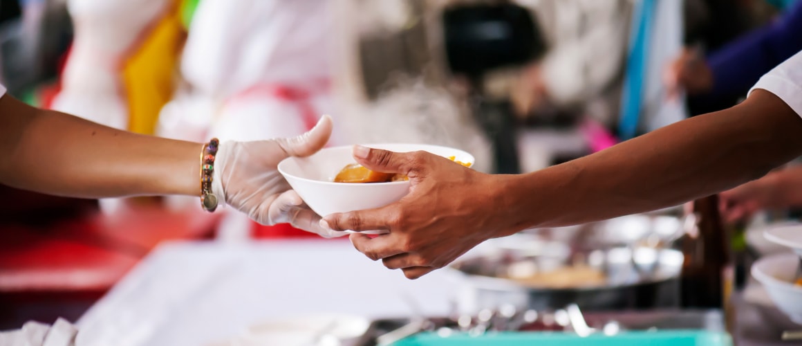 A student worker serving a bowl of food to another student.