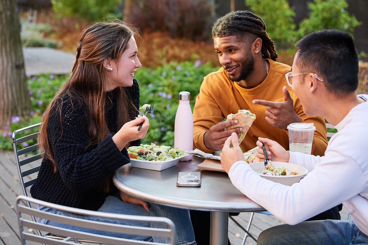 College students talking and eating lunch outdoors.