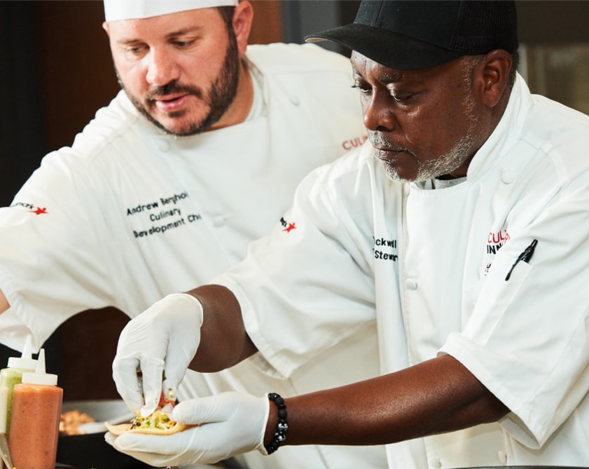 Two Aramark chefs carefully preparing food.