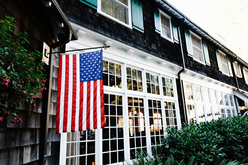 A colonial building with an American flag hanging outside.