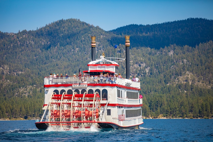 A riverboat on the water against a landscape of mountains.