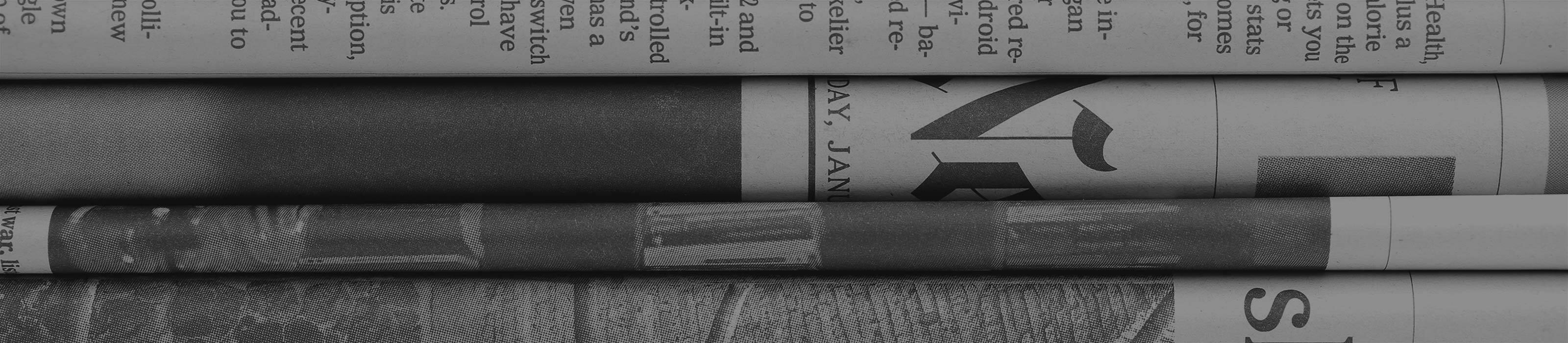 Stacked black and white newspapers.